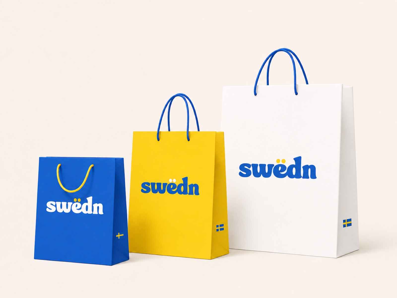 Three Swëdn paper carrier bags in blue, yellow, and white, each with the swëdn wordmark and a small Swedish flag near the base.